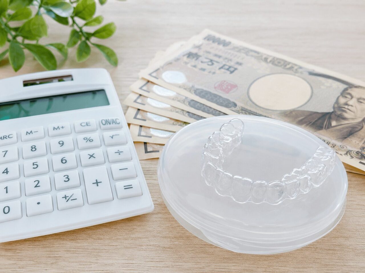 電卓とマウスピースで矯正費用を示すイメージ